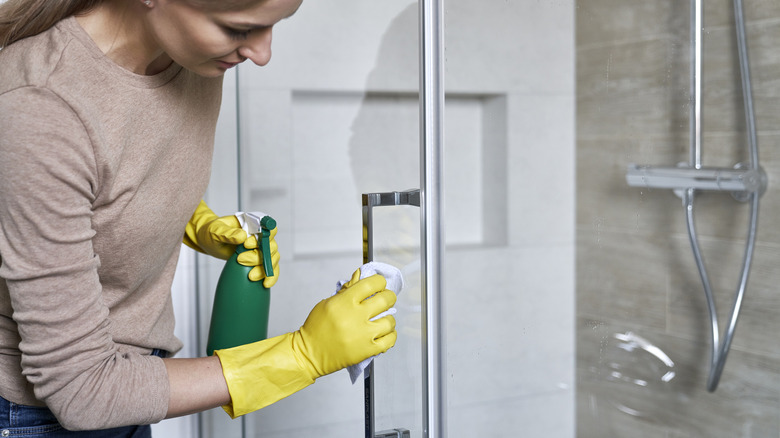Close-up of a woman cleaning a small section of shower glass