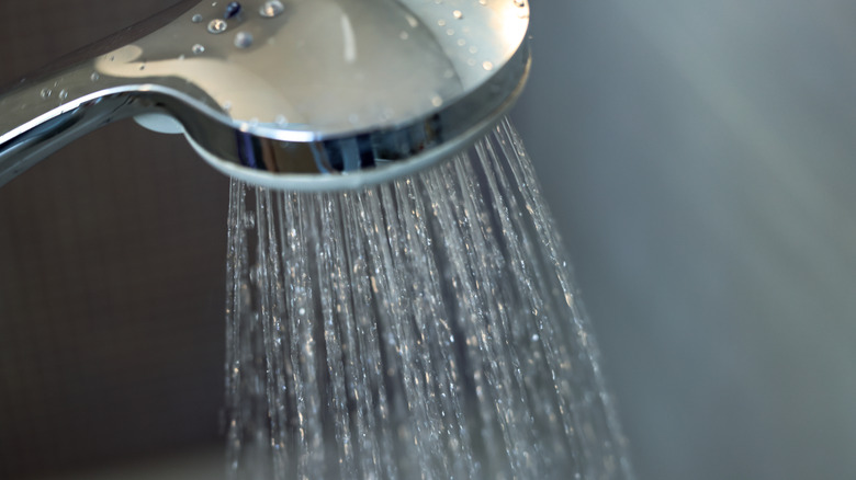 A sleek chrome shower head with water pouring out of it