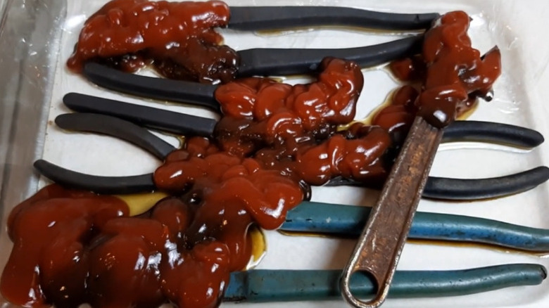 Several pliers and a wrench are on a tray, covered in globs of ketchup