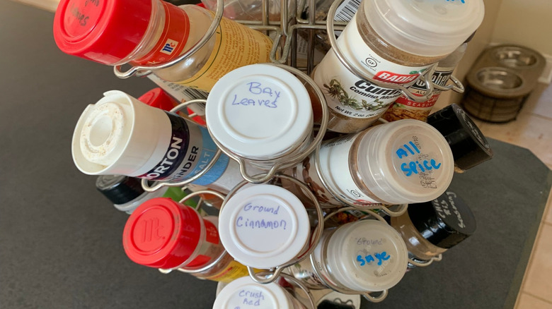Metal silver coffee pod holder filled with various bottles of spice, each labeled with their name on top