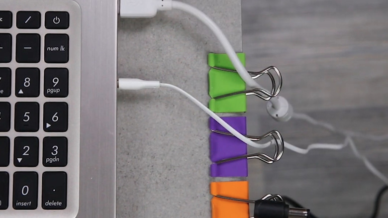 Colorful binder clips on desk edge holding computer cables.