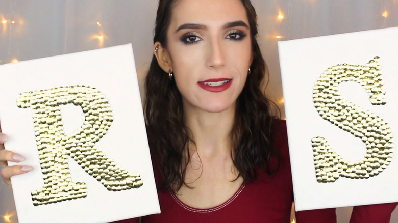 White canvases with letters R and S formed by gold thumbtacks.