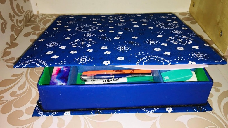 Blue fabric-covered box organizer made from an old binder.