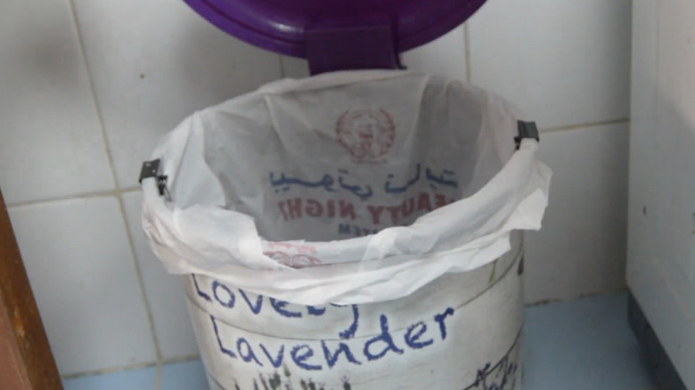 Black binder clips holding white trash bag to rim of bin.