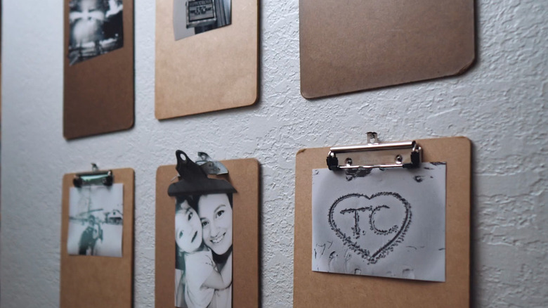 Gallery wall featuring clipboards holding black and white photos.