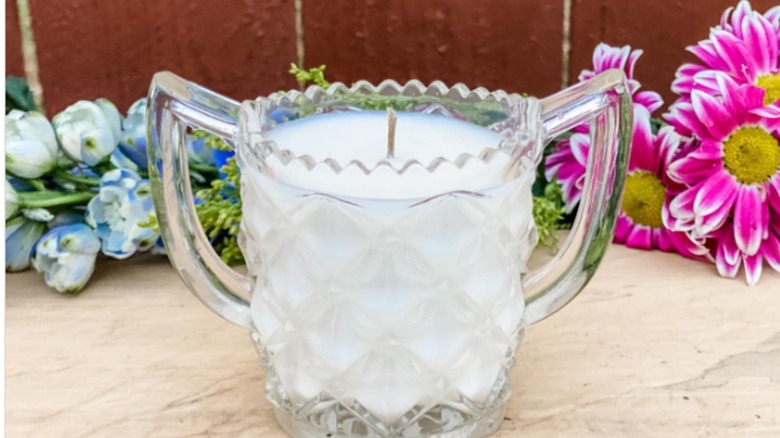 A candle in a vintage crystal creamer