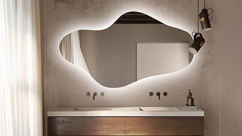 A modern neutral bathroom with an irregular mirror.