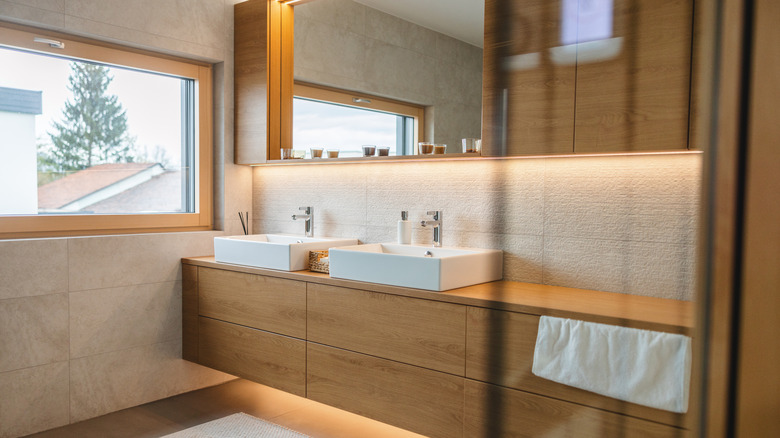 A beige modern bathroom with wood cabinets