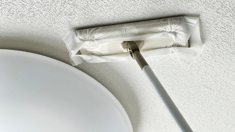Cleaning a textured ceiling with a single-use microfiber mop.