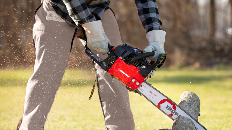 Person using the Troy-Bilt TB4620 chainsaw to cut limbs outside on the ground