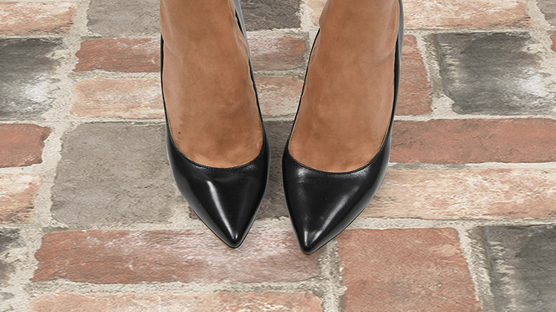 A retro orange brick style tile floor underneath green cabinets.