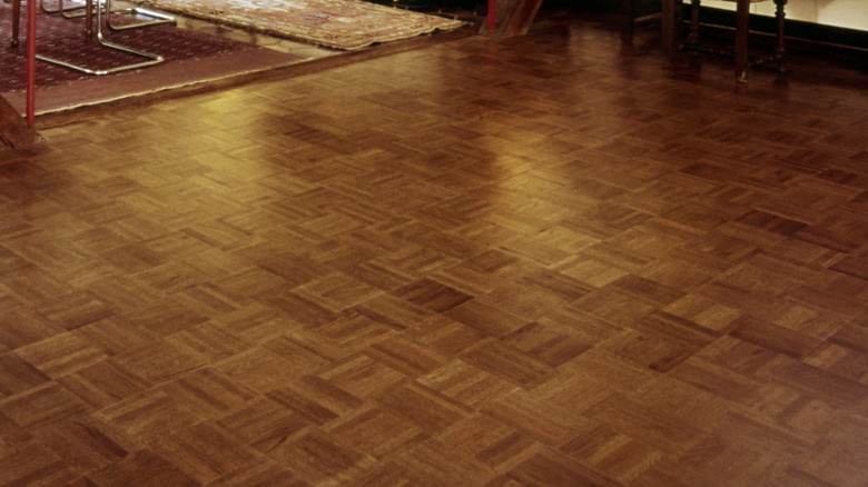 A retro living room with parquet finger block floors, plush white sofa, and modern wall art.