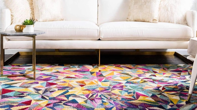 A rainbow geometric rug and white sofa.