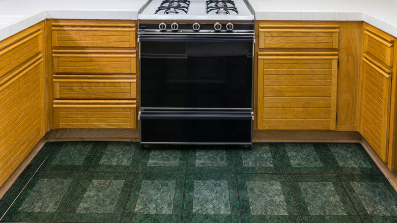 A 1980s kitchen with green vinyl tile floors beneath oven.