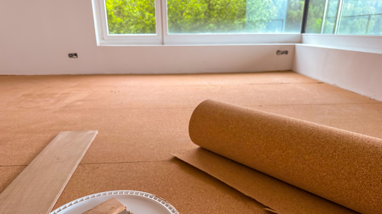 Cork flooring with a roll of cork in a room with large windows.