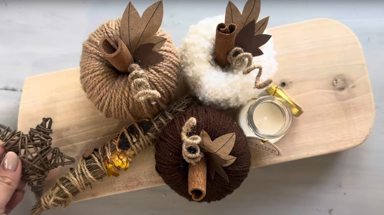 Mini pumpkins in neutral colors with cinnamon sticks on cutting board