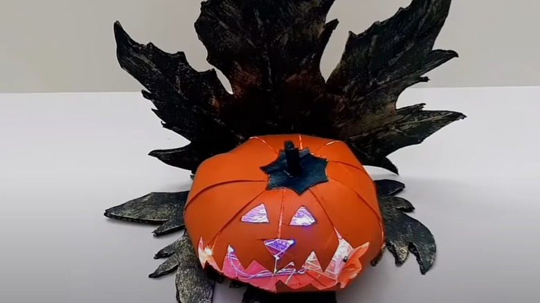 Toilet paper pumpkin on cardboard fall leaf backdrop