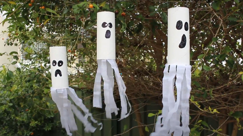 Toilet paper ghosts hanging in trees as fall decor