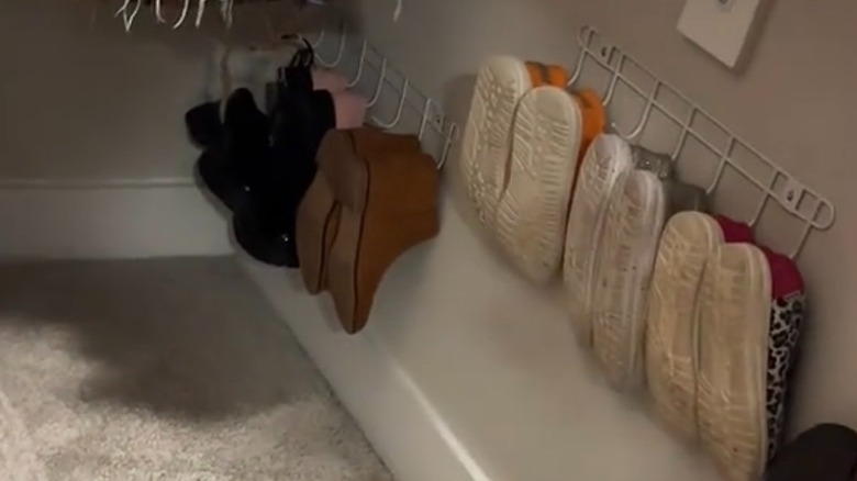 Wire racks mounted on wall of closet with shoes hanging from them