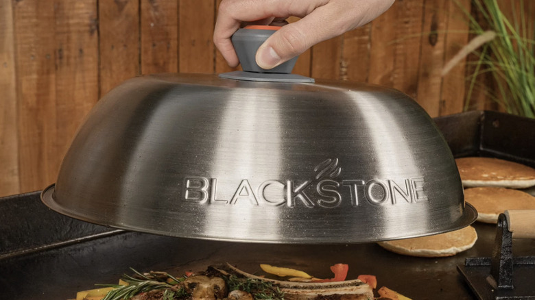 Blackstone griddle cover being lifted off of food