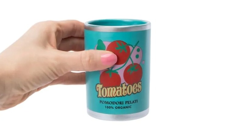 A hand holding a tomato-print pen holder