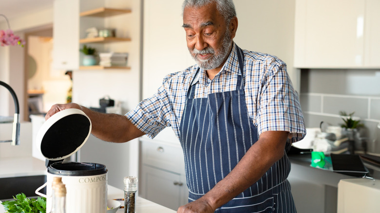 Man in an apron opening a countertop composter