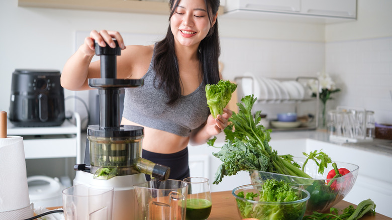 Young woman using a juicing machine to make vegetable juice