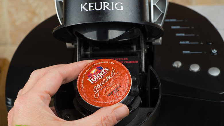 Closeup of a hand inserting a pod into a Keurig coffee maker