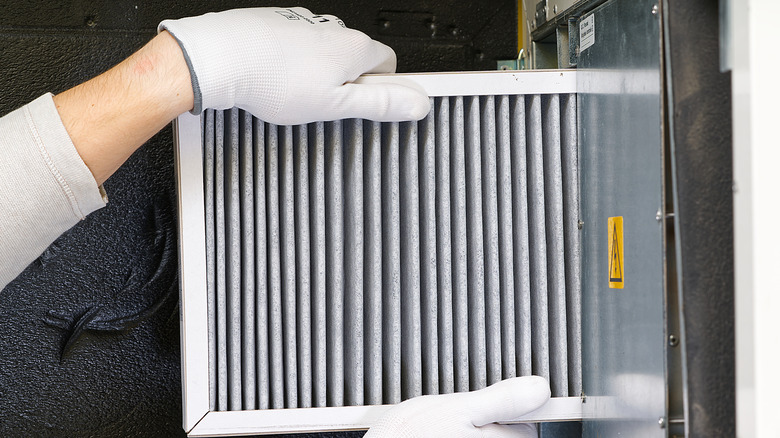 Hands replacing HVAC filter