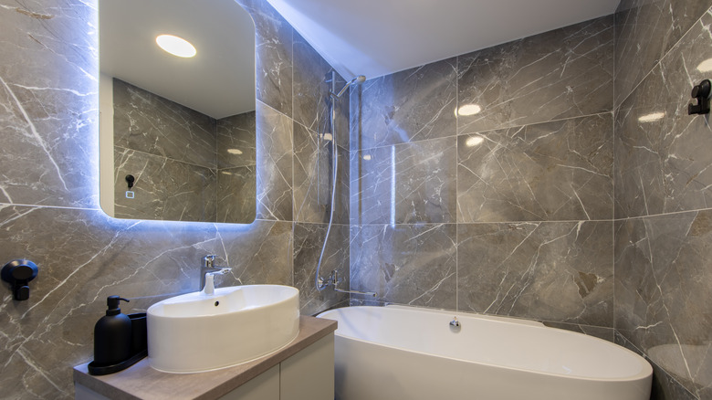 Back lit over-sink mirror in marble tile bathroom