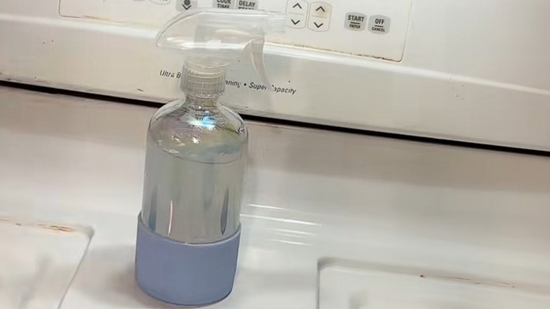 A tinted glass spray bottle on a white stove