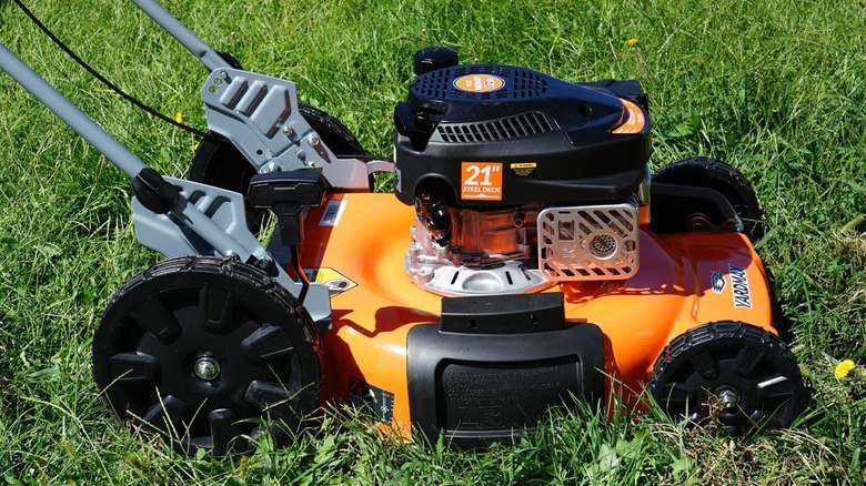 Orange Yardmax lawn mower mowing grass during daytime