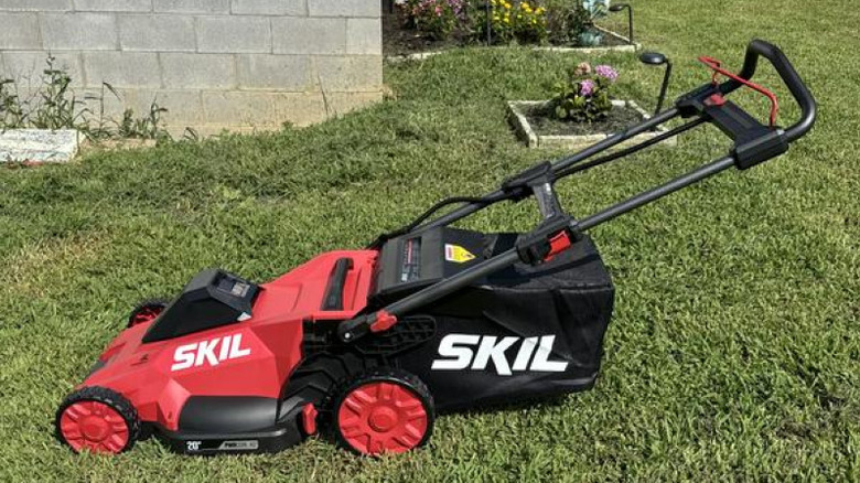 Red SKIL push mower with grass clippings catcher on mowed grass