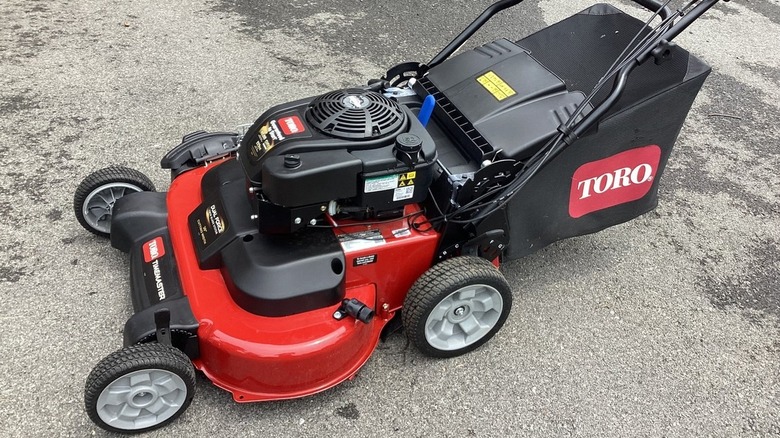 Simple red Toro push mower on grass with grass clipping bag prepped