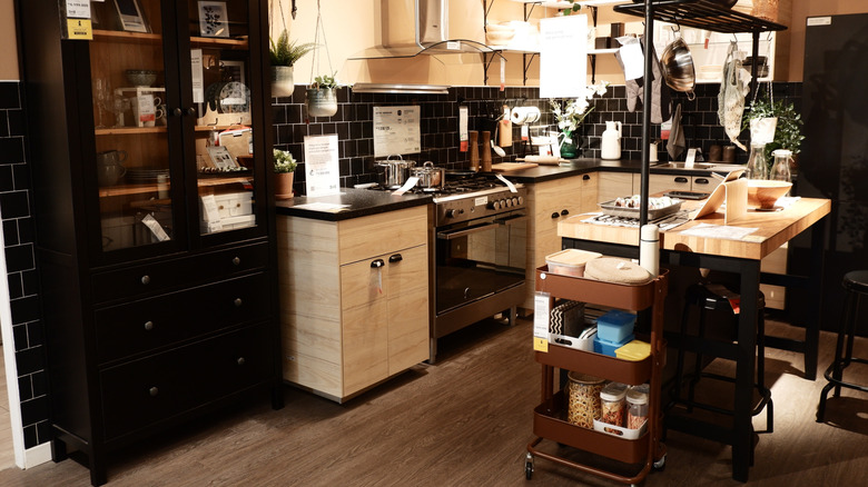 Ikea store kitchen display with light wood cabinets and brown RASKOG cart