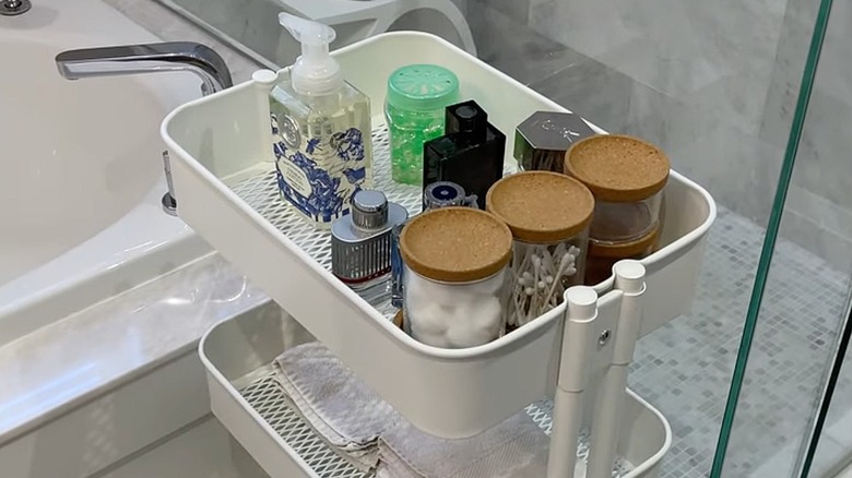 Bathroom supplies in the top shelf of a white RASKOG cart