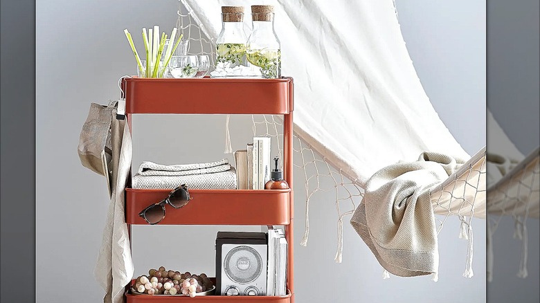 Red cart full of drinks, sunglasses, towels, books, and hand lotion