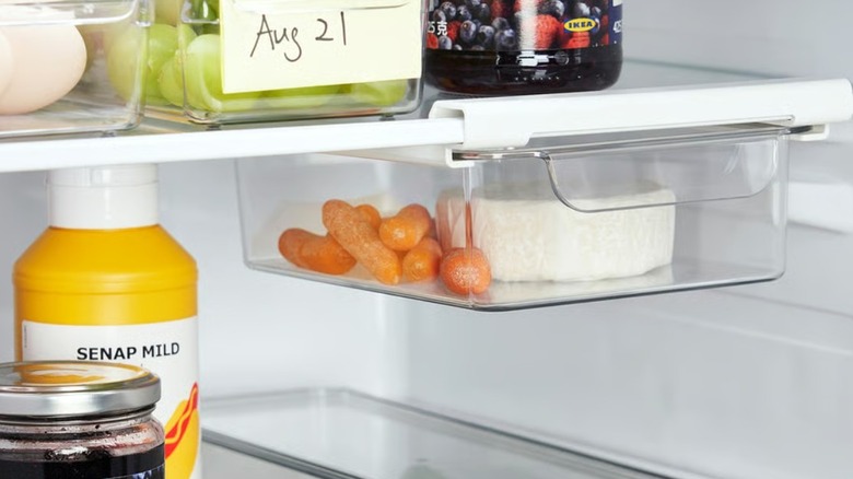 A clear fridge organizer with carrots and cheese