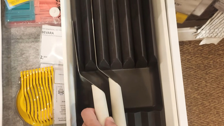 Hand inserting knives into IKEA plastic knife rack