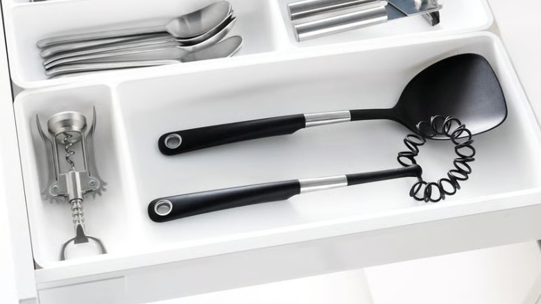 Organized kitchen utensils in white trays in drawer