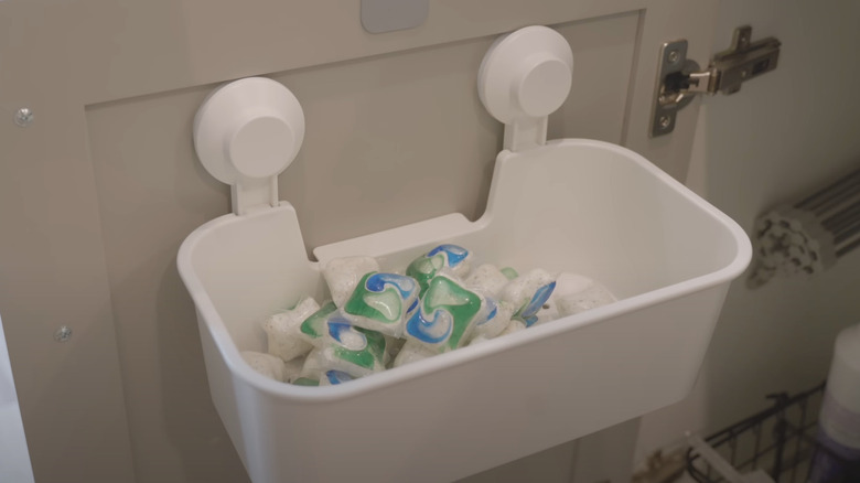 IKEA plastic suction cup basket holding dishwasher pods on cabinet