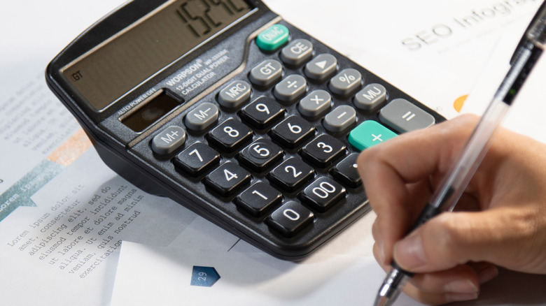 Person using calculator and writing down information for planning purposes