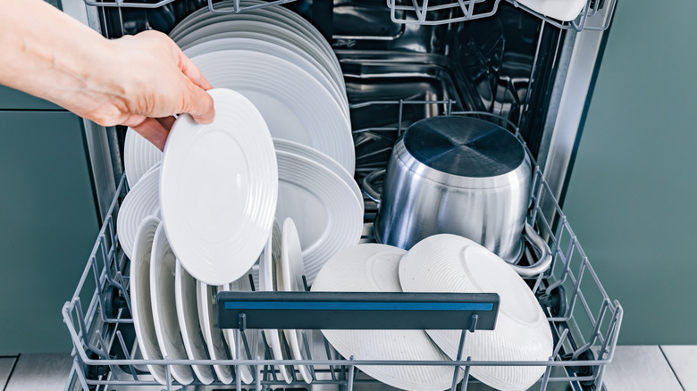 hand unloading very full dishwasher