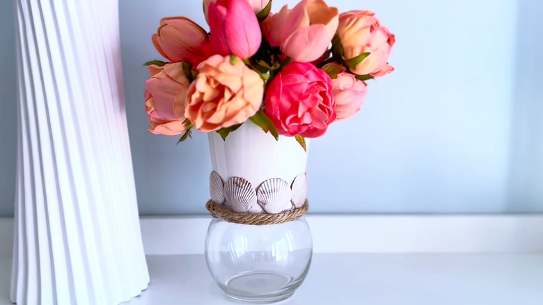 Pink flowers in coastal planter made with shells, twine, and glass vase