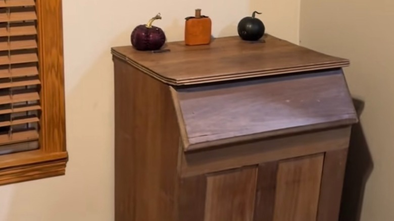 Vintage wood furniture piece repurposed into a hidden trash can