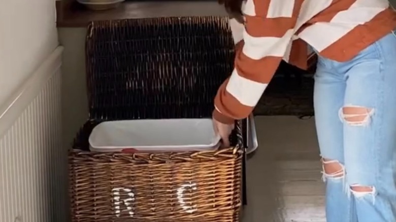 Woman changing out trash can in a wicker laundry hamper
