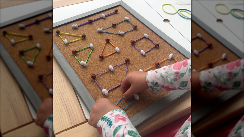 Child making shapes on cork board