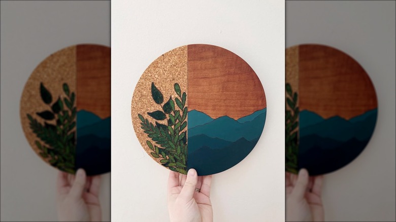 Hand holding painted round cork board art