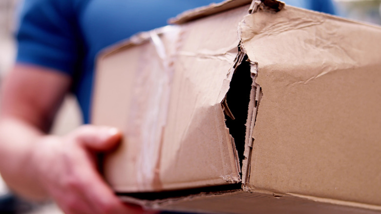 A close up on a crushed cardboard box being held by a person.