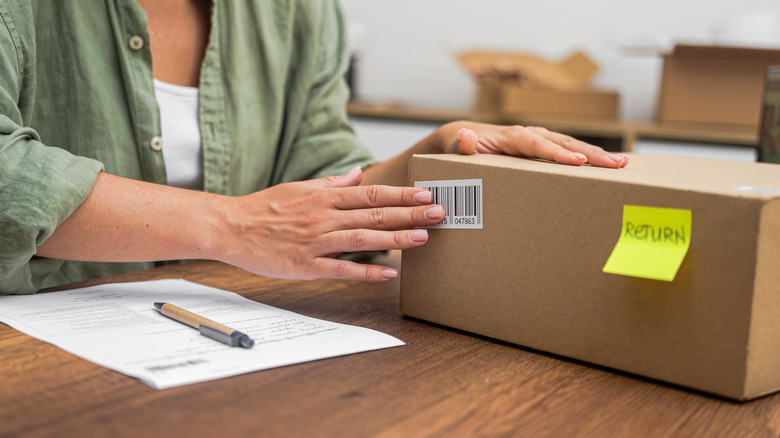 A woman putting a barcode sticker on a box return.